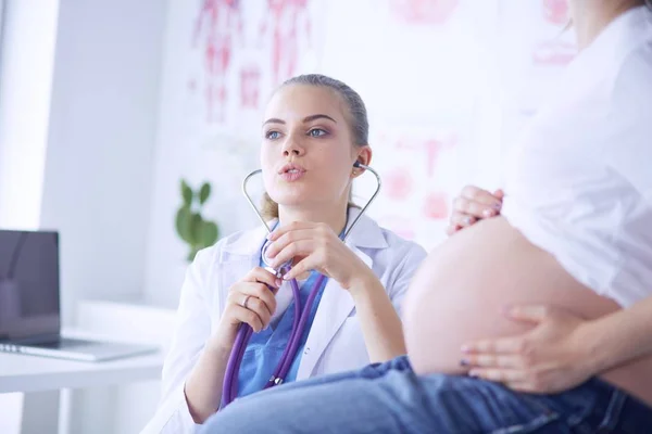 Νεαρή γυναίκα γιατρός που εξετάζει έγκυο γυναίκα στην κλινική. — Φωτογραφία Αρχείου