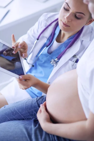 Ung kvinnlig läkare undersöker gravid kvinna på kliniken. — Stockfoto