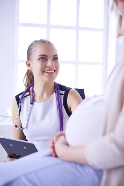 Doctora joven con estetoscopio y tableta que habla con una mujer embarazada en el hospital. — Foto de Stock
