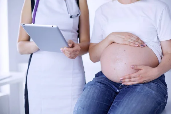 Doctora joven examinando a una mujer embarazada en la clínica. — Foto de Stock