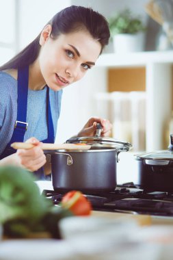 Mutfakta ahşap kaşıkla yemek pişiren kadın