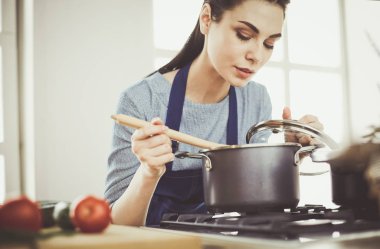 Mutfakta ahşap kaşıkla yemek pişiren kadın