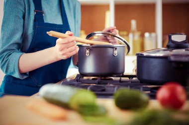 Mutfakta ahşap kaşıkla yemek pişiren kadın