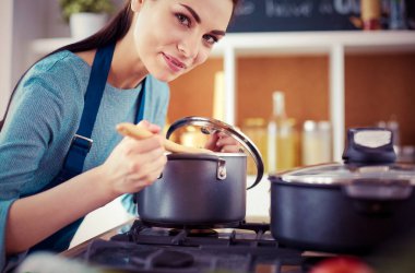 Mutfakta ahşap kaşıkla yemek pişiren kadın