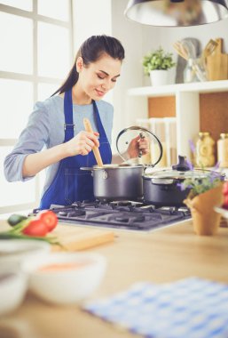 Mutfakta ahşap kaşıkla yemek pişiren kadın