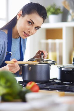 Mutfakta ahşap kaşıkla yemek pişiren kadın