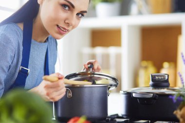 Mutfakta ahşap kaşıkla yemek pişiren kadın