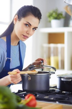 Mutfakta ahşap kaşıkla yemek pişiren kadın