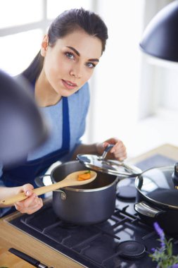 Mutfakta ahşap kaşıkla yemek pişiren kadın