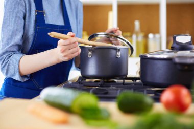 Mutfakta ahşap kaşıkla yemek pişiren kadın