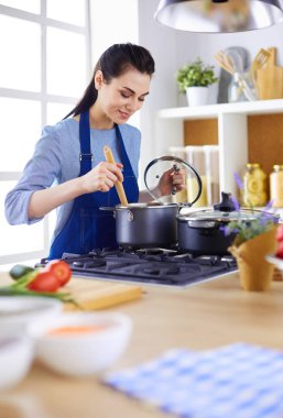 Mutfakta ahşap kaşıkla yemek pişiren kadın