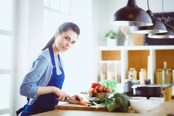 Fiatal nő vágás zöldségek a konyhában otthon — Stock Fotó