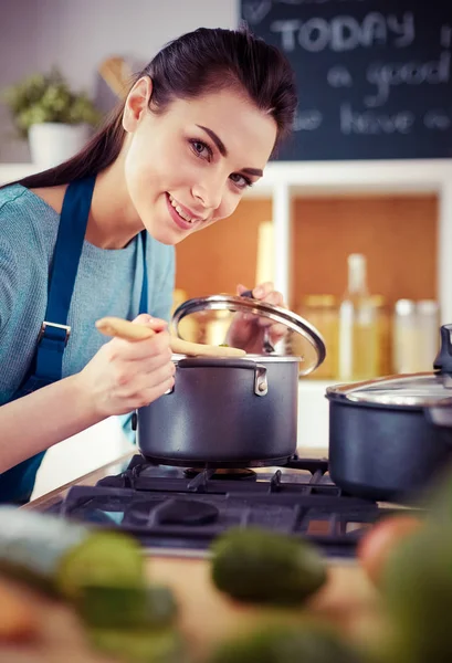 Mutfakta ahşap kaşıkla yemek pişiren kadın — Stok fotoğraf
