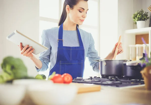 Mladá žena pomocí tabletu počítače vařit ve své kuchyni — Stock fotografie