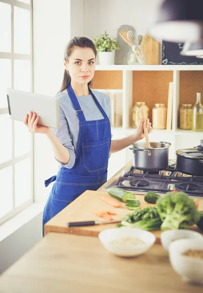 Junge Frau kocht mit Tablet-Computer in ihrer Küche — Stockfoto