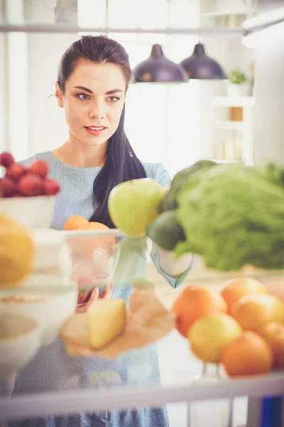 Smiling woman taking a fresh fruit out of the fridge, healthy food concept — Stock Photo, Image