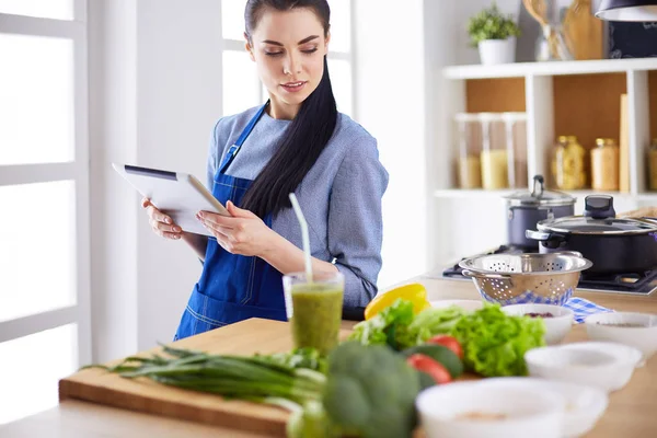 Junge Frau kocht mit Tablet-Computer in ihrer Küche — Stockfoto