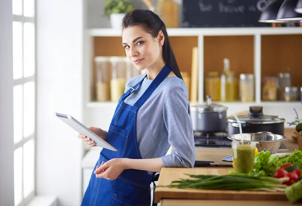 Mujer joven usando una tableta para cocinar en su cocina — Foto de Stock