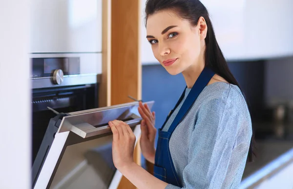 Hermosa joven comprobando cómo le va a su pastel en el horno —  Fotos de Stock