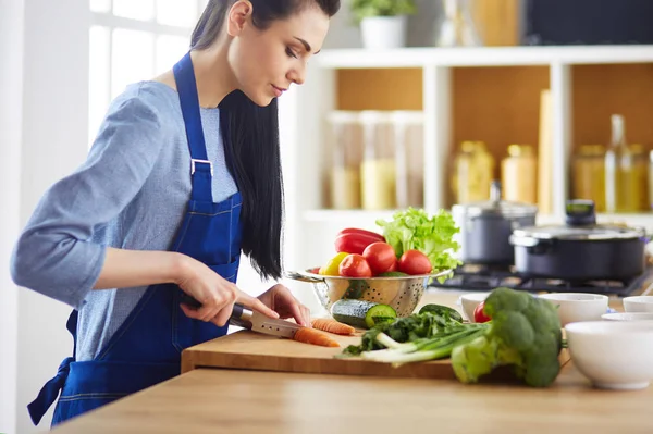 Junge Frau schneidet Gemüse in Küche zu Hause — Stockfoto