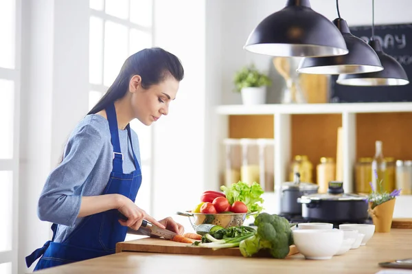 Jovem mulher cortando legumes na cozinha em casa — Fotografia de Stock