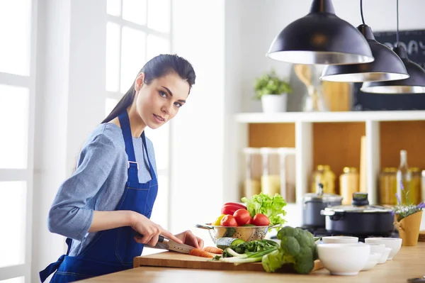 Junge Frau schneidet Gemüse in Küche zu Hause — Stockfoto