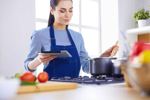 Junge Frau kocht mit Tablet-Computer in ihrer Küche — Stockfoto