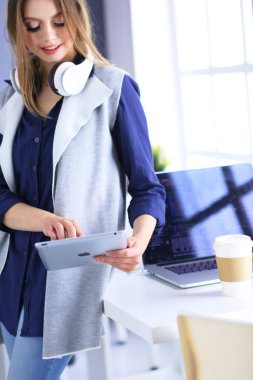 Ofis masasında çalışan ve dizüstü bilgisayarla yazan kendine güvenen genç bir iş kadını.