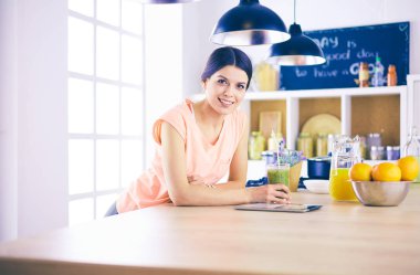 Mutfakta dijital tablet kullanan güzel genç bir kadın..