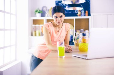 Mutfakta dizüstü bilgisayara benzeyen tariflerle gülümseyen genç bir kadın. Gıda blogcusu kavramı.