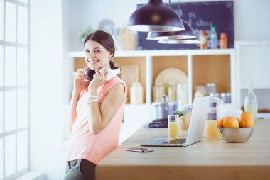 Mutfakta dizüstü bilgisayara benzeyen tariflerle gülümseyen genç bir kadın. Gıda blogcusu kavramı.