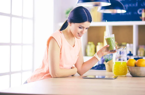 Vacker ung kvinna med hjälp av en digital tablett i köket. — Stockfoto