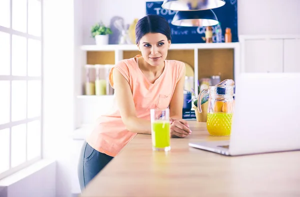 Egy fiatal nő a konyhában laptoppal, aki recepteket keres, mosolyog. Élelmiszer blogger koncepció. — Stock Fotó