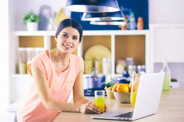 厨房里的年轻女人带着手提电脑看菜谱，面带微笑。粮食博客概念. — 图库照片