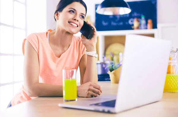 Mujer joven en la cocina con computadora portátil buscando recetas, sonriendo. Concepto de bloguero de alimentos. —  Fotos de Stock