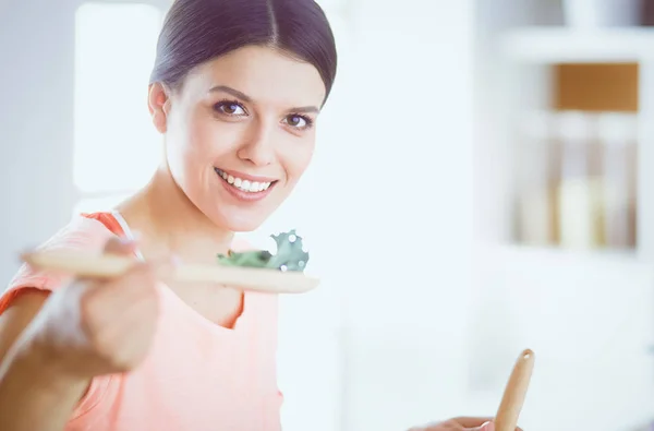 Mujer joven sonriente mezclando ensalada fresca en la cocina. —  Fotos de Stock