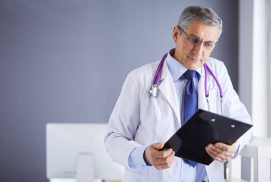 Erkek doktor hastanedeki panoya notlar yazıyor.