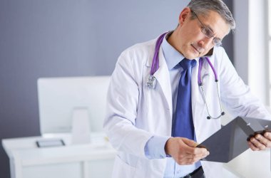 Erkek doktor hastanedeki panoya notlar yazıyor.