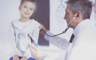 Steteskoplu kız ve doktor kalp atışlarını dinliyor.