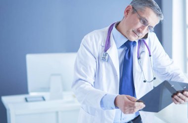 Erkek doktor hastanedeki panoya notlar yazıyor.