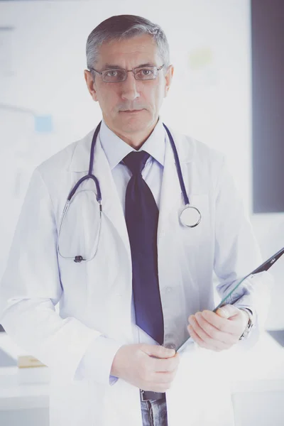 男性医師は病院のクリップボードにメモを書きます — ストック写真