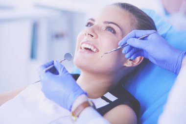 Dişçi muayenehanesinde diş muayenesi yapan ağzı açık genç bir kadın hasta..