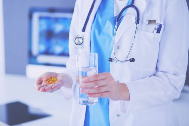 Doktorlar ellerinde haplar ve klinikte bir bardak su tutarken..