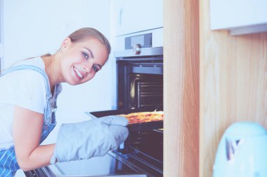 Mutlu genç bayan evde pizza pişiriyor.