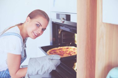 Mutlu genç bayan evde pizza pişiriyor.