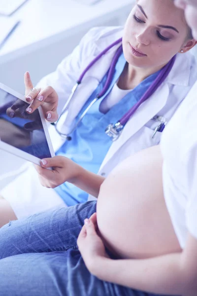 Ung kvinnlig läkare undersöker gravid kvinna på kliniken. — Stockfoto