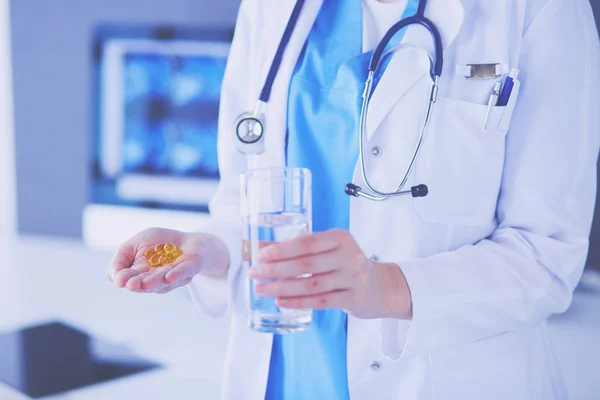 Coup de mains de médecins tenant des pilules et un verre d'eau à la clinique. — Photo