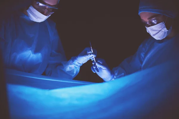 Orvosok csapat a műtét egy sötét háttér. — Stock Fotó