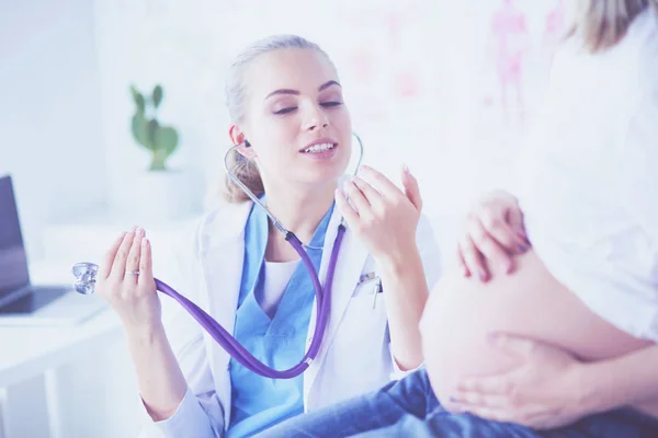Giovane donna medico con stetoscopio che parla con una donna incinta in ospedale. — Foto Stock