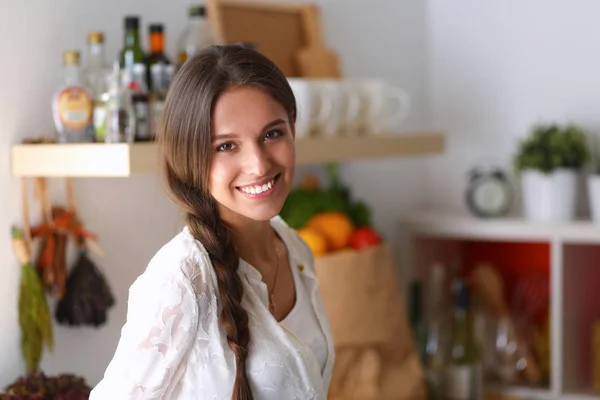 Mujer joven de pie cerca de escritorio en la cocina —  Fotos de Stock